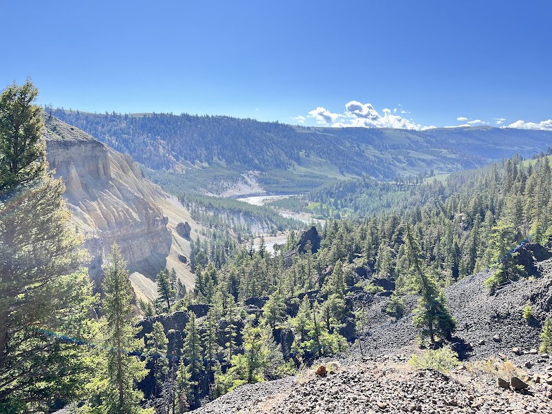 Wraith Falls Trailhead overlooks a forested canyon, winding river, and distant hills in Yellowstone National Park.