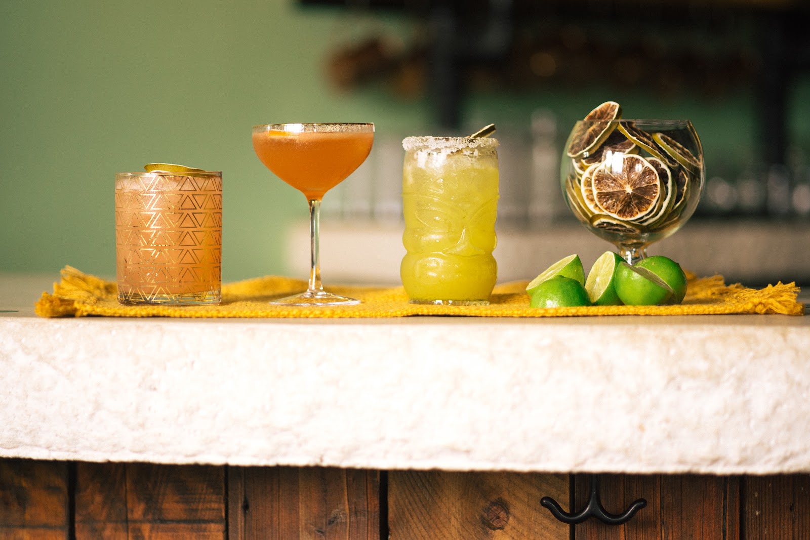 Assorted cocktails on a bar counter with lime wedges and citrus garnishes at a Glacier National Park establishment.