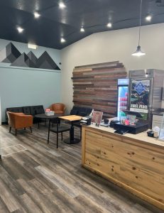 Interior of a Glacier National Park creamery cafe with a wooden counter, lounge seating, and modern pendant lighting.