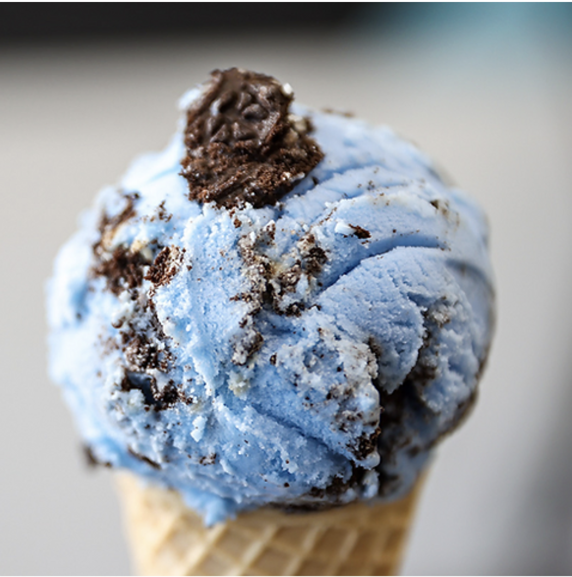 Close-up of a blue ice cream scoop with chocolate chunks in a waffle cone at Glacier National Park.