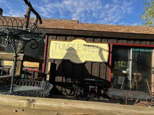 Exterior view of a rustic storefront with wooden accents and a hanging sign