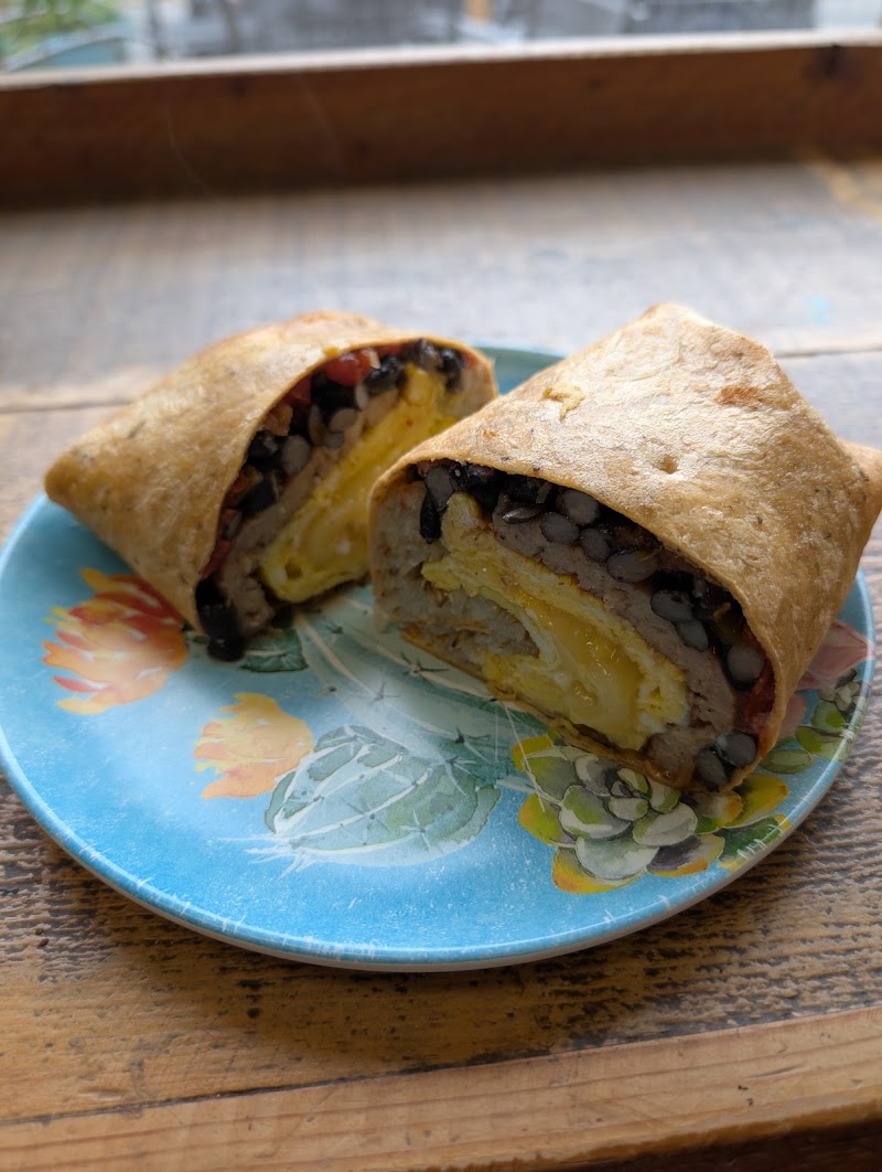 Two folded burritos sliced in half reveal black beans, melted cheese, and egg on a blue floral plate outdoors in Yellowstone National Park.