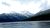 Long Knife Peak looms snowcapped above a dark forest and tranquil lake in Glacier National Park.