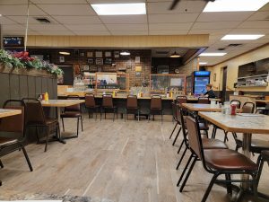 Cozy Glacier National Park dining room with a long counter, brick walls, and rows of brown chairs.