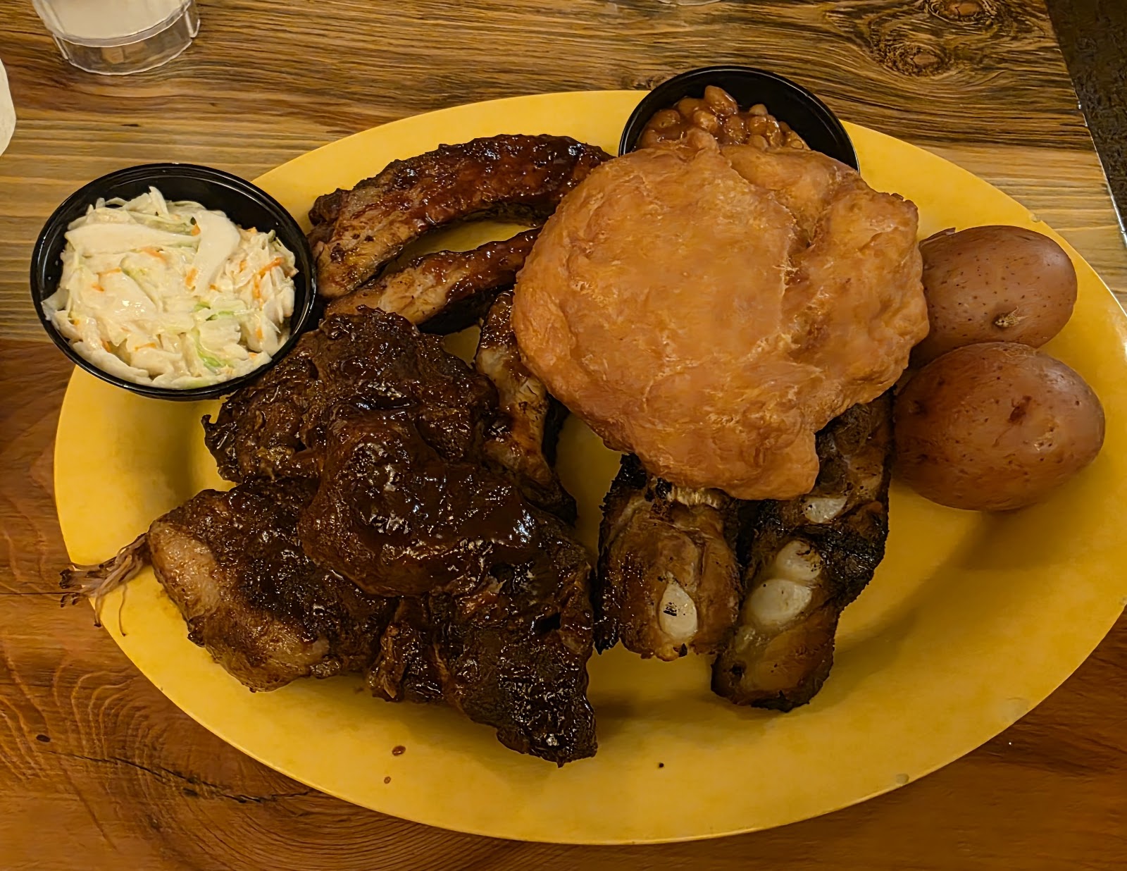 Hearty barbecue platter at a Glacier National Park dining spot featuring ribs, chicken, potatoes, and sides.