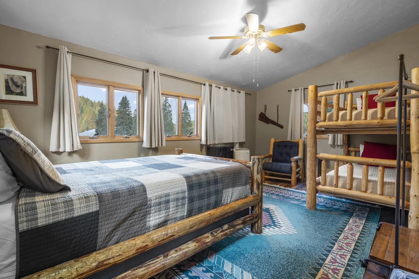Rustic log bunk-room in a lodge at Glacier National Park, with forest views through the windows.