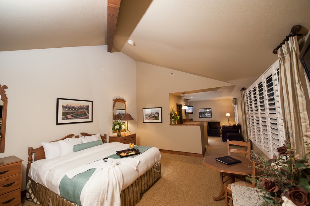 Bright guest room at a lodge in Glacier National Park with a king bed, teal accents, and warm lighting.