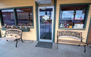Sushi restaurant storefront in Glacier National Park with yellow siding and green trim on a sunny day.