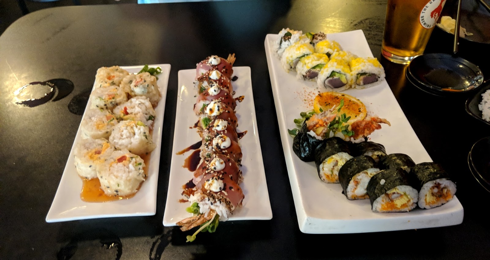 Assorted sushi rolls and nigiri served on white platters at a Glacier National Park dining area.