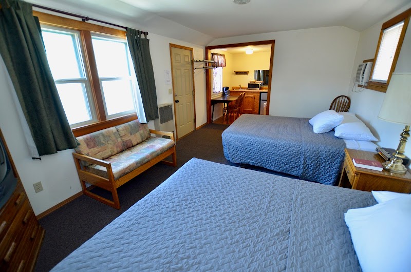 Two double beds with blue quilts in a cozy lodge room at Yellowstone National Park, plus a small sofa by the window.