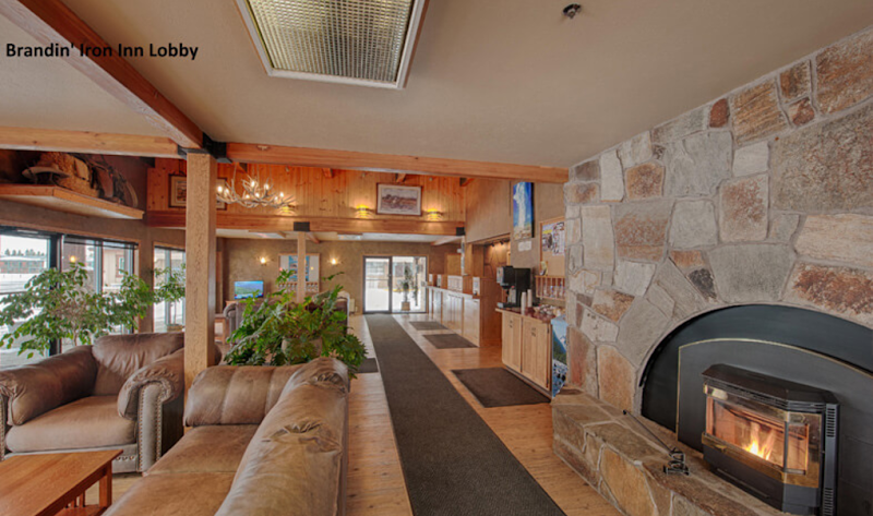 Cozy lodge lobby in Yellowstone National Park with a stone fireplace, leather sofas, wooden beams, and a front desk.