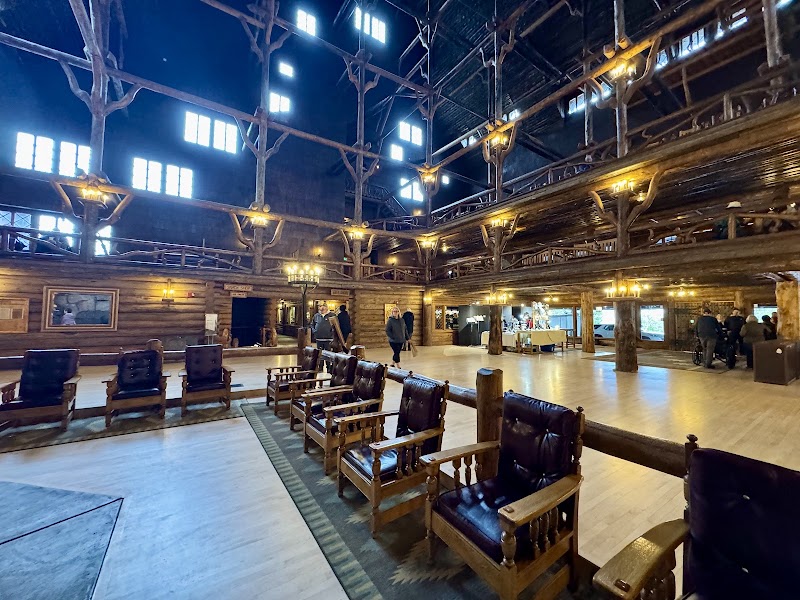 Rustic lodge interior in Yellowstone National Park featuring multi‑level balconies, leather chairs, and warm lighting.