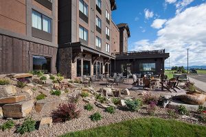 Outdoor patio at a lodge in Glacier National Park, with seating, rock landscaping, and mountain views.