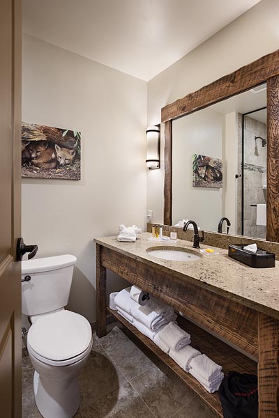 Lodge bathroom vanity in Glacier National Park with a granite countertop, wooden frame, and stacked towels.