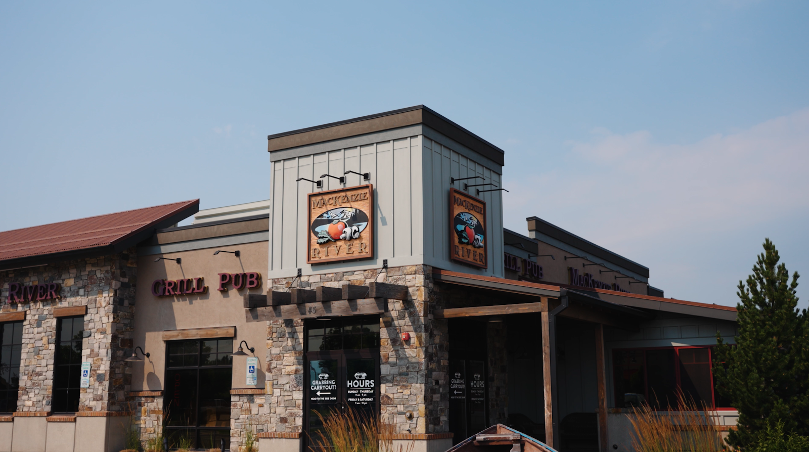 Glacier National Park restaurant exterior housed in a stone-and-slate building with a river-themed sign and warm lighting.