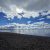 Fishing Bridge area along Yellowstone Lake shores, calm water, sandy beach, and dramatic cloudy sky.
