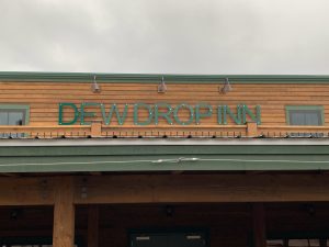 Exterior of a wooden inn-style building with teal signage in Glacier National Park.