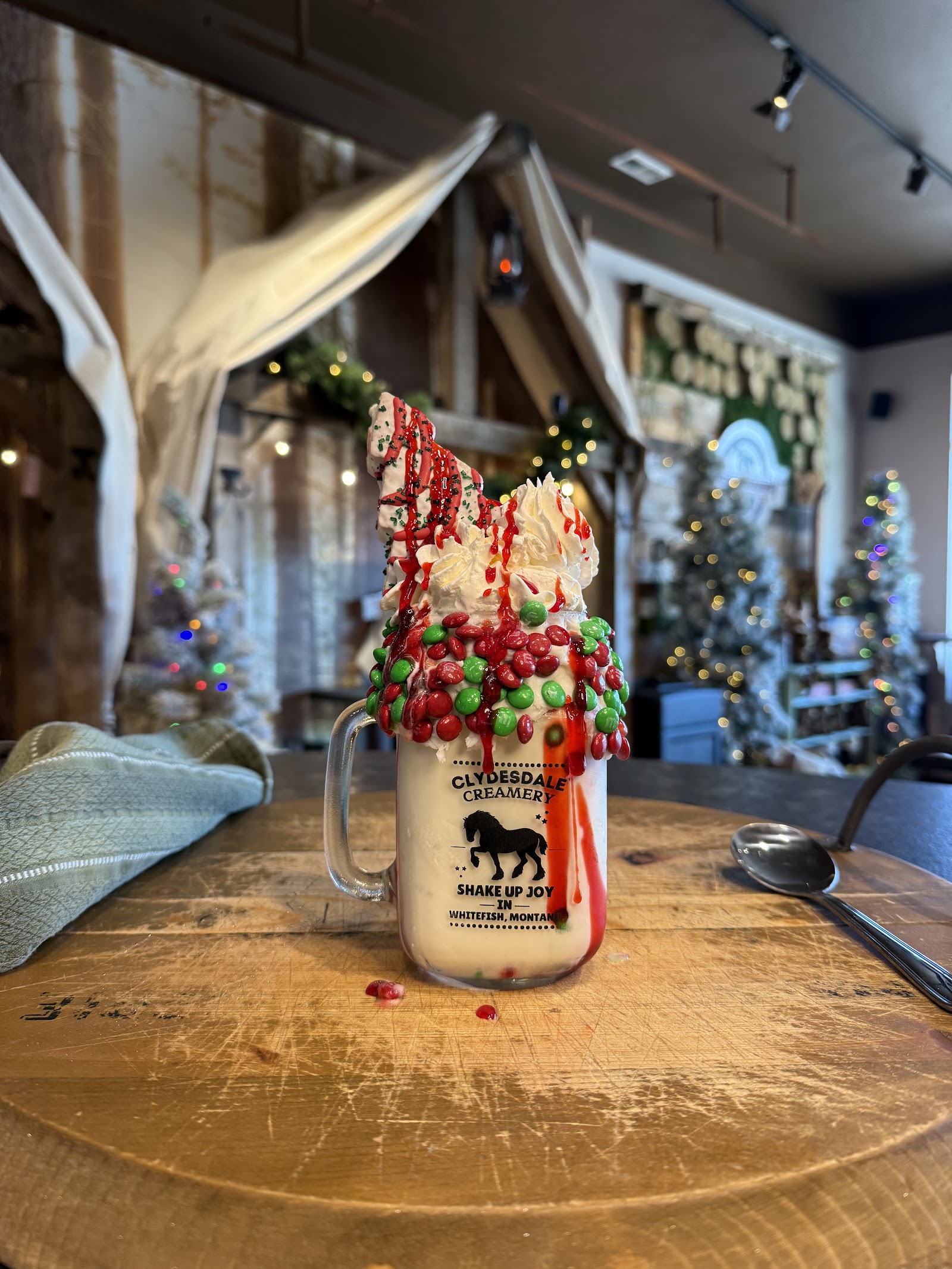 Milkshake at Clydesdale Creamery in Glacier National Park, topped with whipped cream, red and green candies, and festive drizzle.
