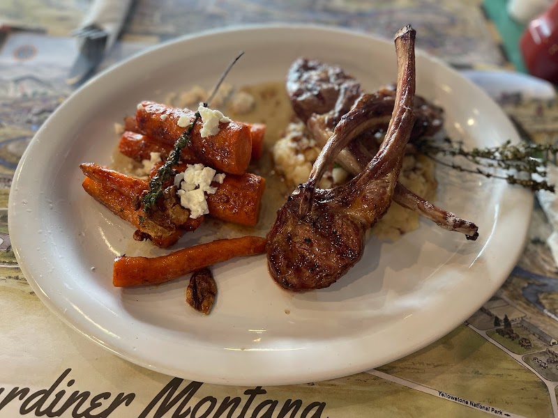 Plate with roasted lamb chop, sweet potato fries, herbs, and mashed potatoes at Yellowstone National Park restaurant.