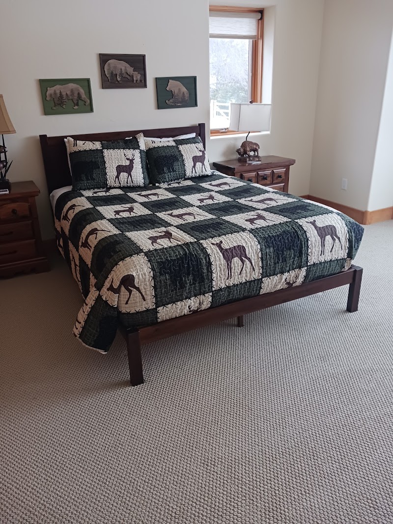 Cozy mountain bedroom at Glacier National Park with dark wood bed, deer-themed quilt, bear art on wall, and twin lamps.