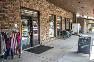 Thrift shop storefront in Glacier National Park displaying clothing racks outside in front of a brick building.