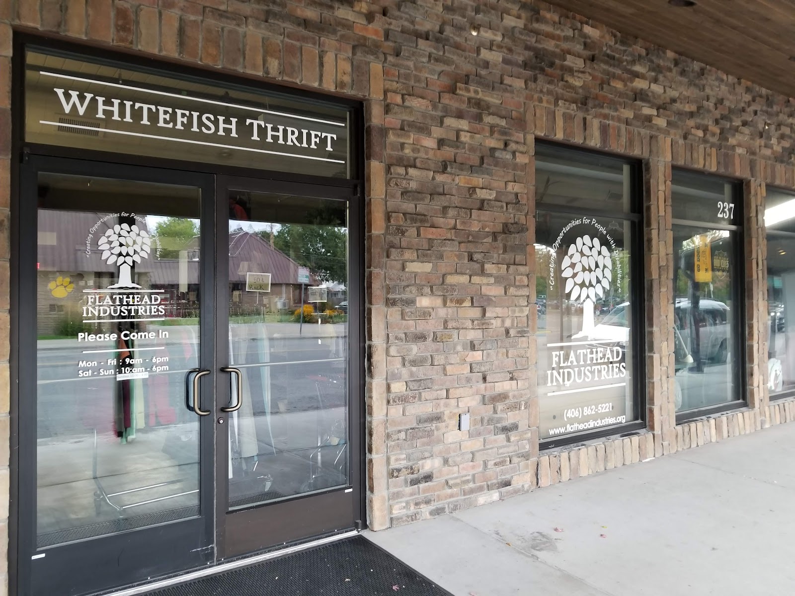 Thrift shop storefront on a brick building in Glacier National Park near Whitefish, with a large window sign.