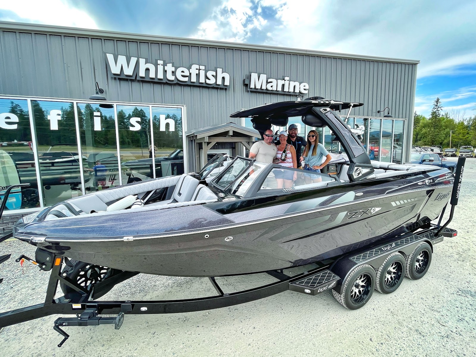 Powerboat on a triple-axle trailer parked outside a marine shop near Glacier National Park.