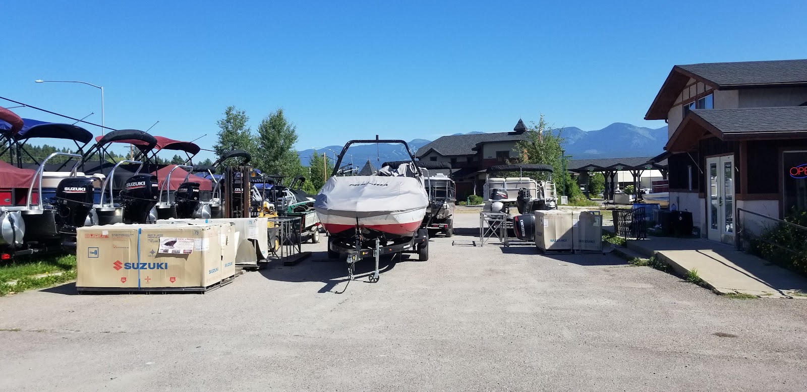 Boat display and marina area near Glacier National Park, with boats on trailers and a storefront visible in the background.