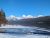 Snow-covered Fish Creek Picnic Area beside a calm lake with snow-dusted peaks in Glacier National Park.