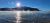 Fish Creek Picnic Area at Glacier National Park, sunlit lake with mist rising from the water and mountain silhouette in the distance.