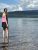 Visitor stands in shallow Fish Creek at the Fish Creek Picnic Area in Glacier National Park, with forested hills beyond.