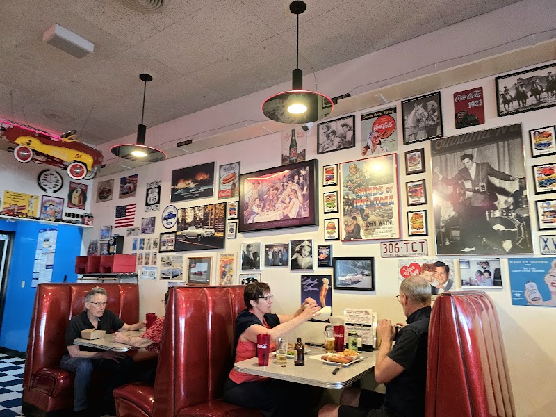 Inside a retro diner at Yellowstone National Park with red vinyl booths, vintage posters on the wall, and diners enjoying burgers.