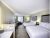Two-queen guest room in Yellowstone National Park featuring modern furnishings, a work desk, and a seating area.