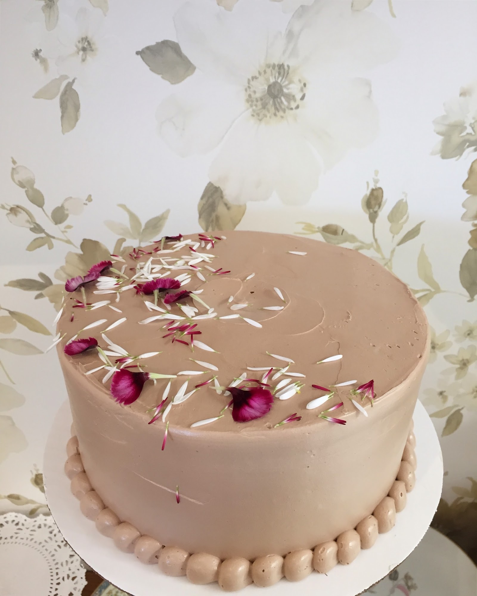 Chocolate cake displayed in Glacier National Park with pink petals and decorative icing.