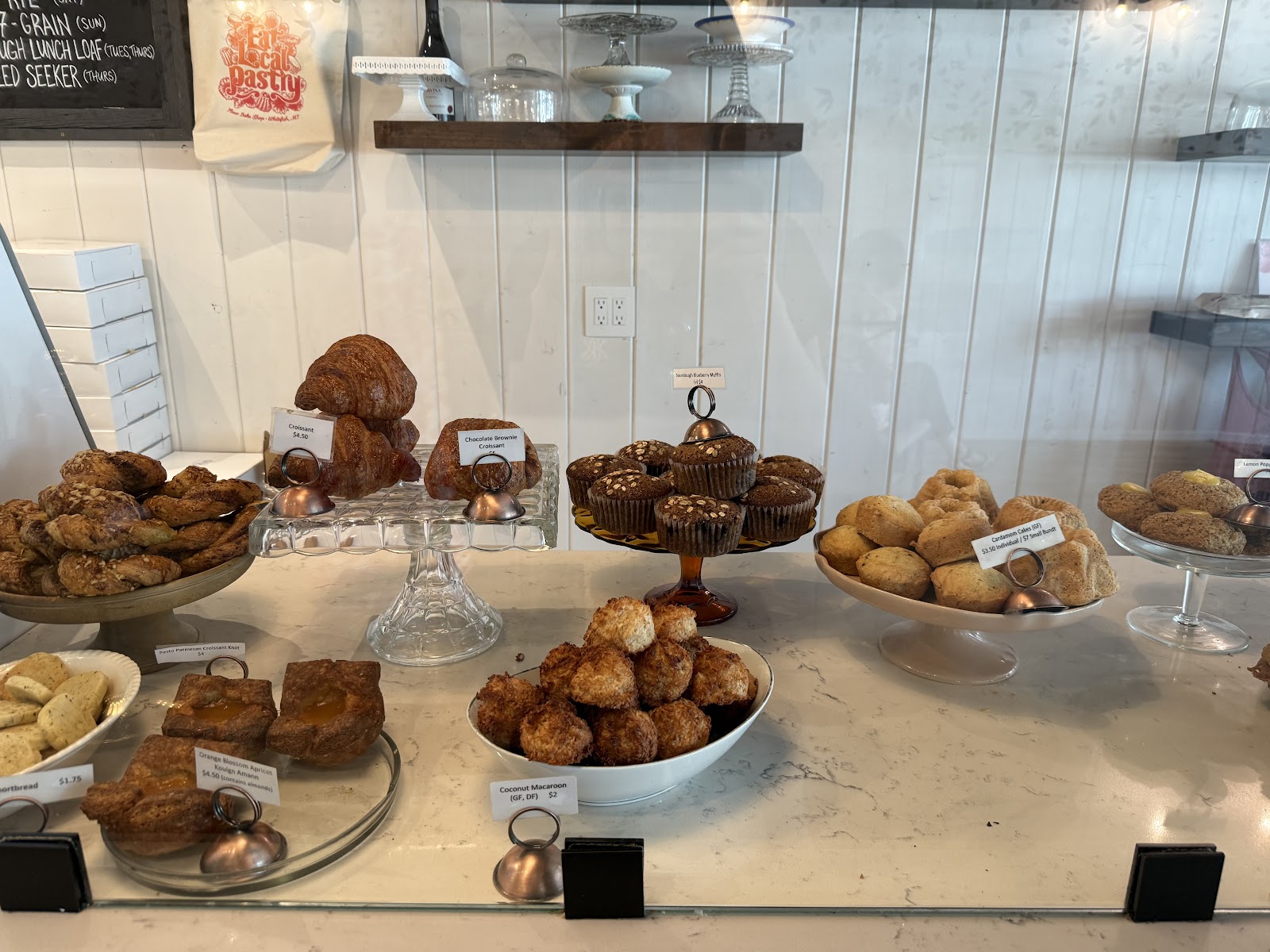 Inside a Glacier National Park bakery display case, an assortment of croissants, muffins, and pastries sit on marble counters.