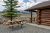 Roosevelt Lodge exterior in Yellowstone National Park with a wooden picnic table and distant snow-capped mountains.