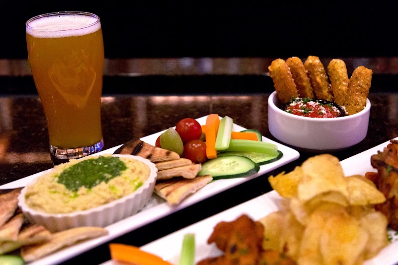 Beer glass beside a veg platter with cucumbers, tomatoes, carrots, pita, hummus, and breadsticks in Yellowstone National Park.