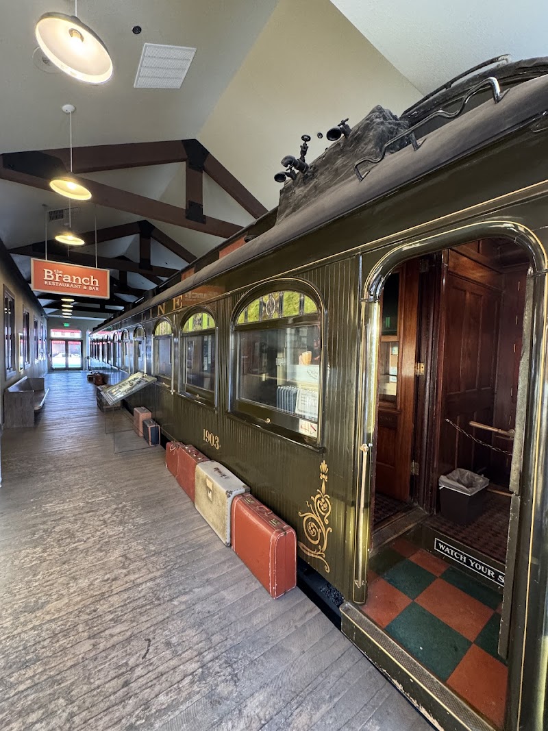 Inside Yellowstone National Park, a vintage green dining train car with gold trim and suitcases lined along the base.