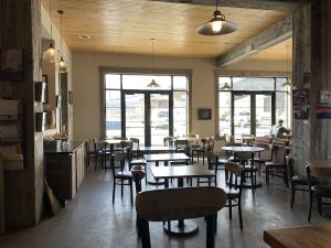 Front storefront with wooden sign and outdoor seating