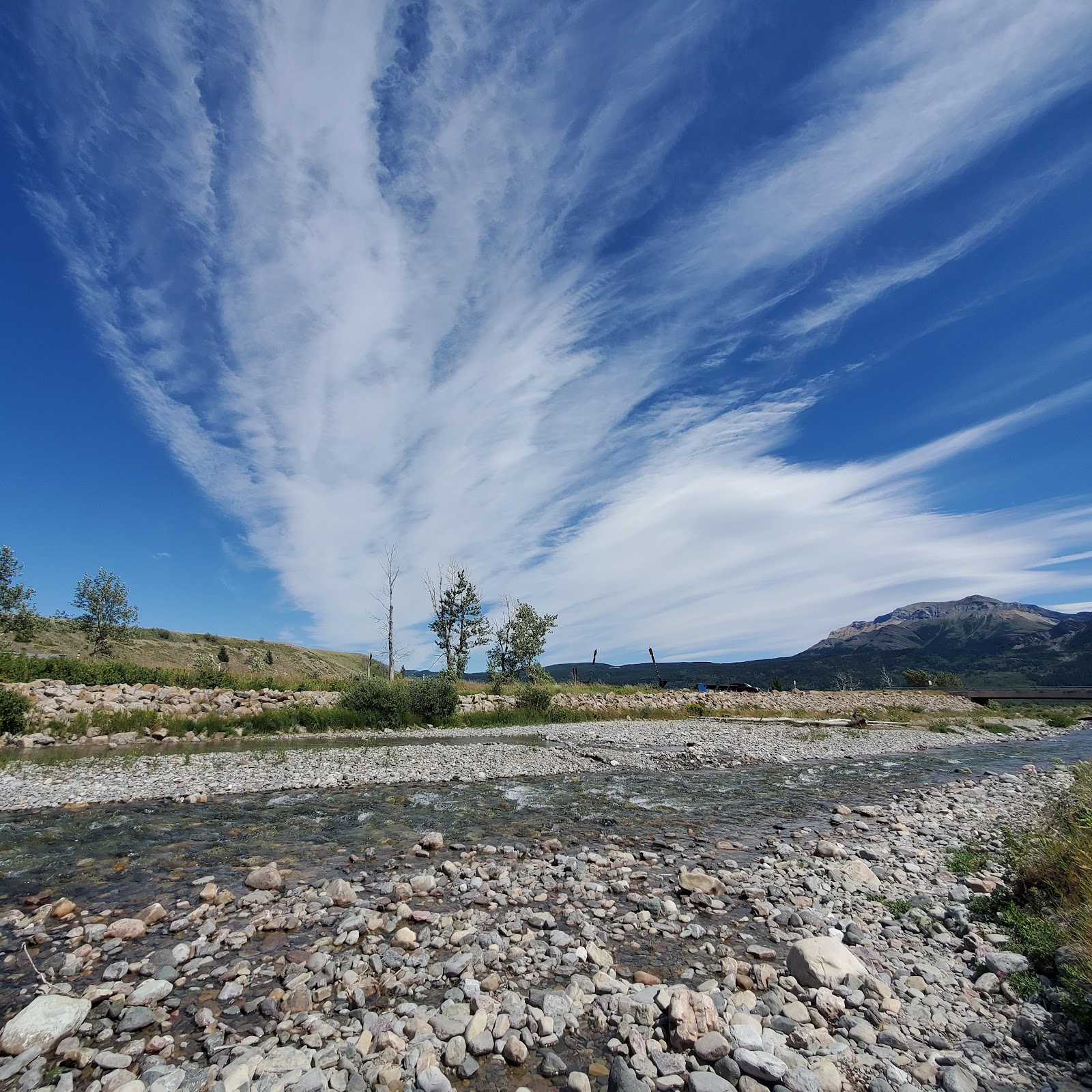 Pass Creek day use area in Glacier National Park beside a rocky riverbank and expansive blue sky.