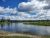 Bakers Hole Campground along the Yellowstone River with forested banks and green islands under a cloudy blue sky.