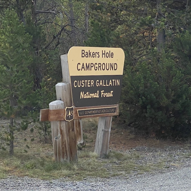 Forested entrance sign for a campground in Yellowstone National Park, supported by wooden posts.