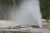 Old Faithful geyser erupts near a wooden boardwalk as visitors watch in Yellowstone National Park.