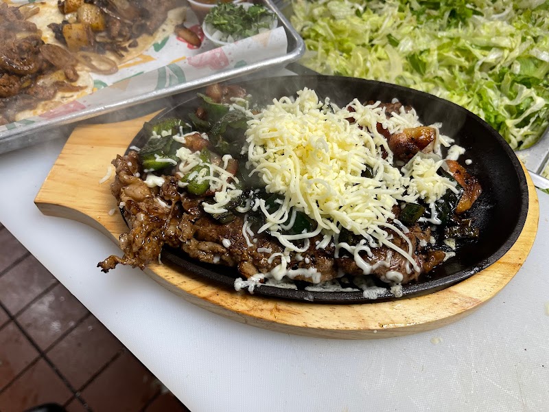 Beef skillet dish with sautéed peppers and melted cheese served hot in Acadia National Park area near a lettuce garnish