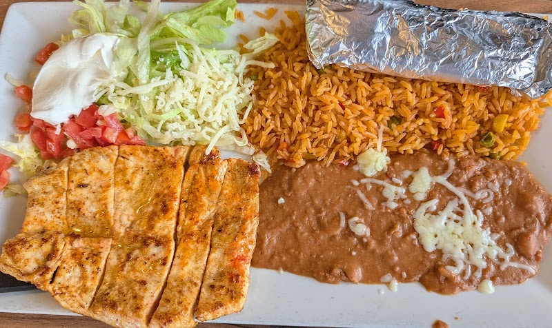 Restaurant meal plate in Acadia National Park, featuring grilled chicken, rice, beans, salad, and a foil-wrapped item.