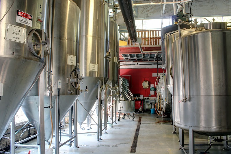 Row of tall stainless steel fermentation tanks and piping inside a brewery setup at Acadia National Park.