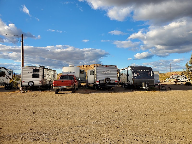 Row of RVs and travel trailers parked at a desert campground in Big Bend National Park, with a bright blue sky overhead.