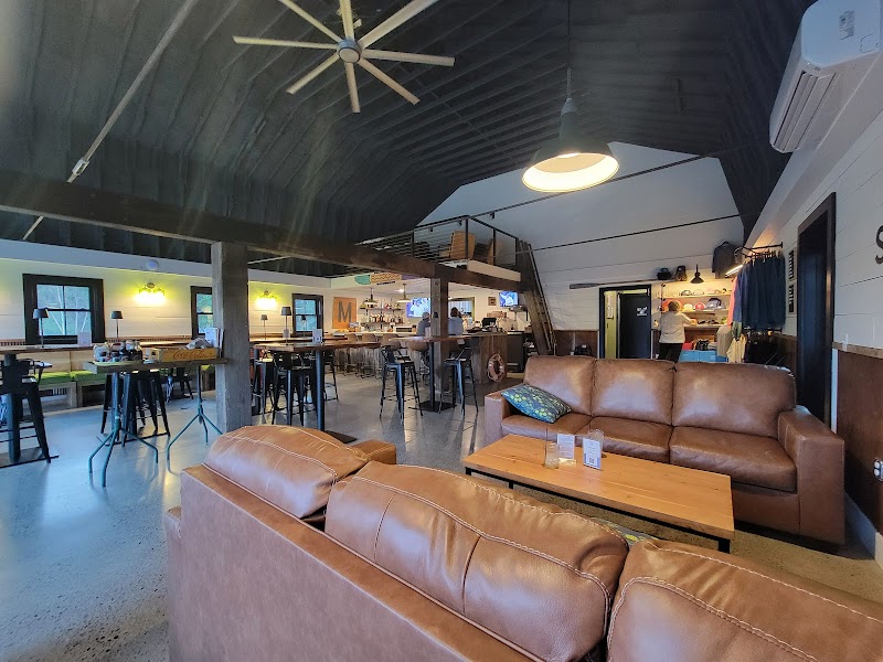 Cozy interior of an indoor brewery seating area inside Acadia National Park with leather couches and communal tables.
