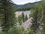Essex area overlook in Glacier National Park shows pine forests, colored ridges, and a winding river.