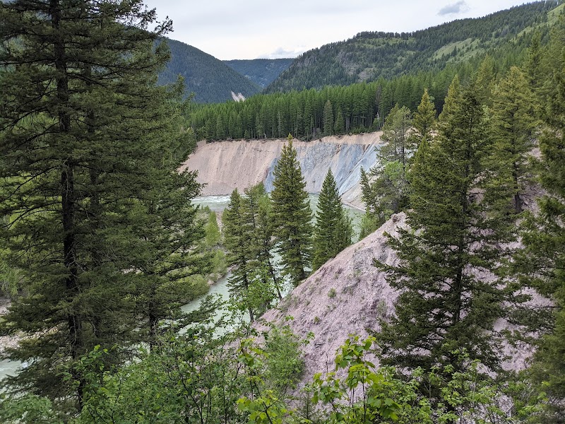 Essex area overlook in Glacier National Park shows pine forests, colored ridges, and a winding river.